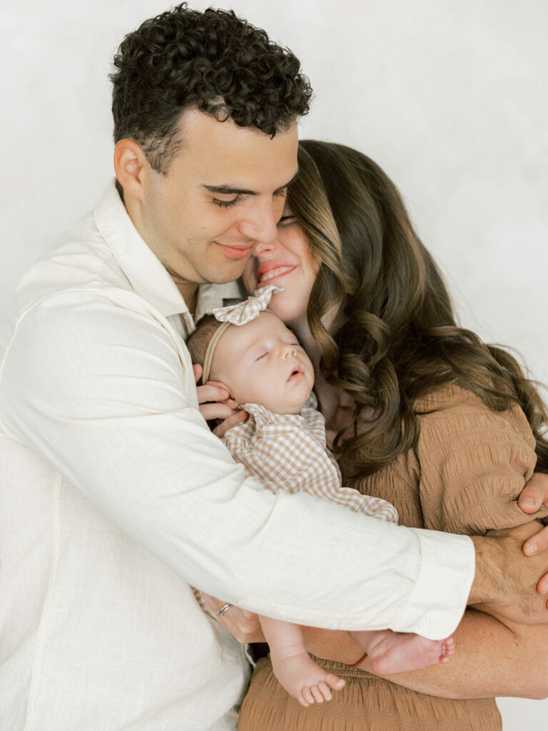 Parents cuddling their newborn baby together during a natural studio newborn session in Santa Clarita