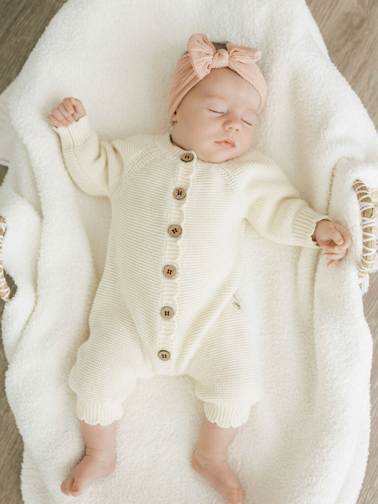 Newborn baby resting on a white blanket during simple studio newborn photos
