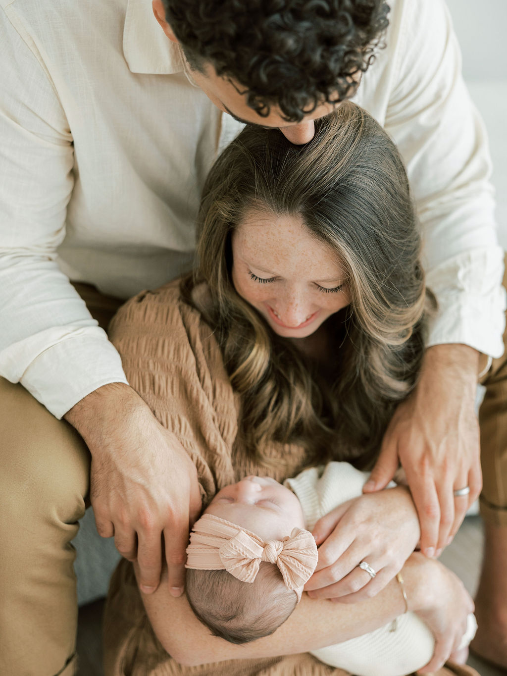 Parents looking down and smiling at their newborn baby during natural family newborn photos
